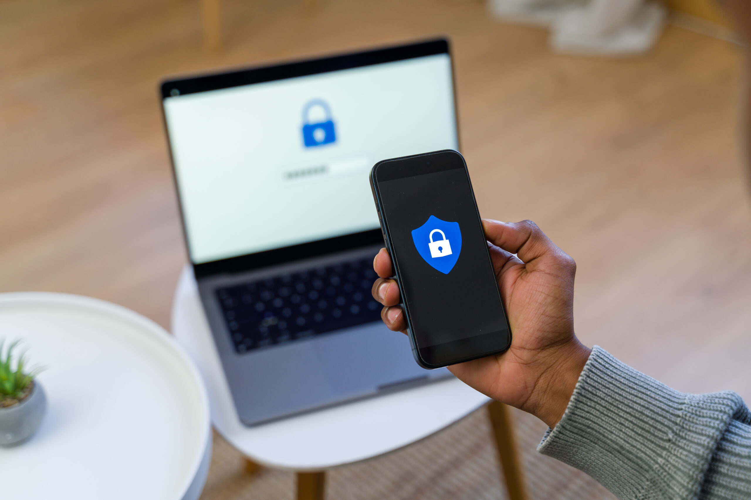 programmer-holding-smartphone-with-security-app-and-laptop-in-background